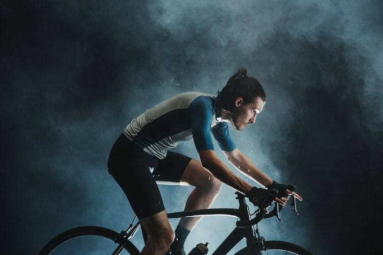 fit man in cycling clothing riding bike dark smoke