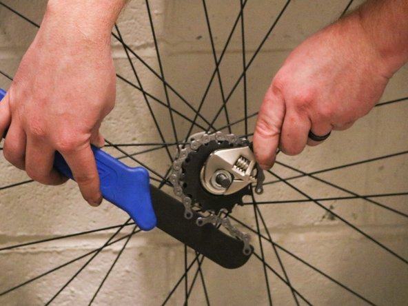 person using wrench tool to fix bike cassete how to