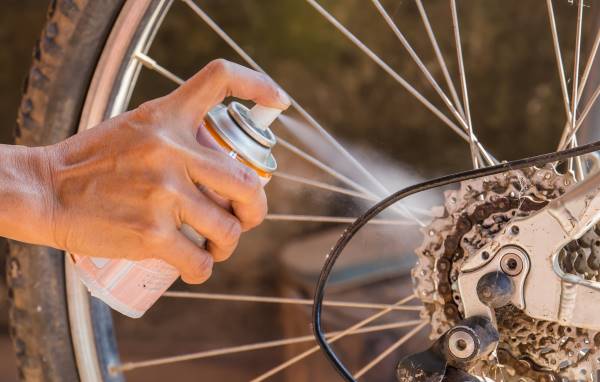 person spraying bike chain Bike chain rust prevention