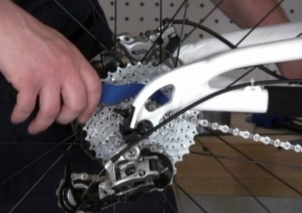 person using tools to fix bike cassete how to clean a bike cassete