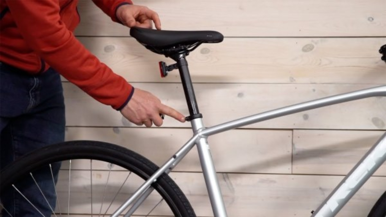 hand pointing at bicycle seat post explain wooden wall