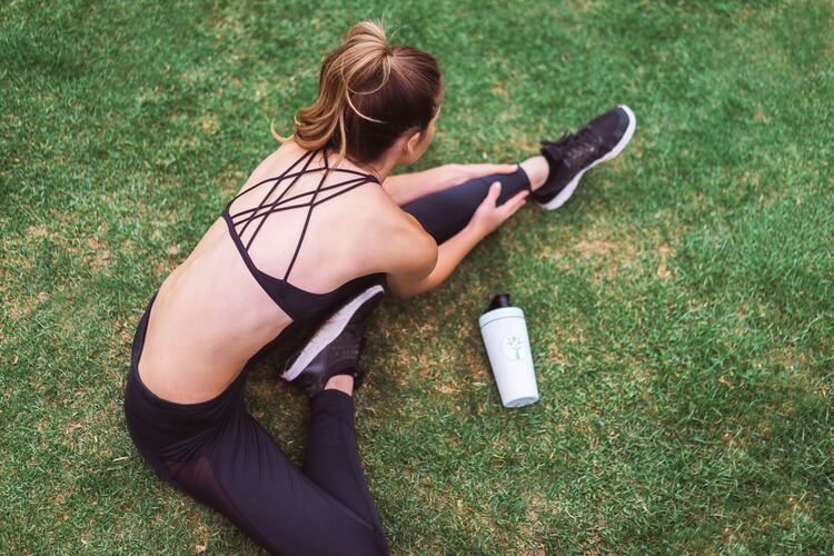 woman in sport bras warm up stretching green grass